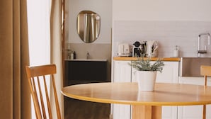 A modern kitchen with white cabinets, a wooden dining table, and a potted plant. - Pure Flor de Esteva (Vila do Bispo)