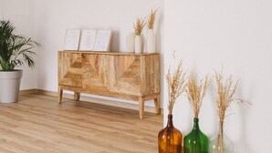 A modern living room with a wooden cabinet, a potted plant, and three vases with dried plants. - Pure Flor de Esteva (Vila do Bispo)