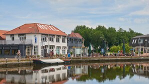 A hotel with a red tiled roof, a canal in front, and a reflection in the water. - Hotel Villa GROET uit Avenhorn (Avenhorn)
