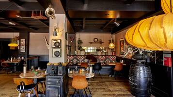 Un restaurante con zona de bar, mesas y sillas de madera.