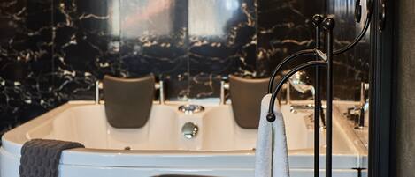Un baño moderno con una bañera independiente, un perchero para toallas y un salpicadero de mármol.