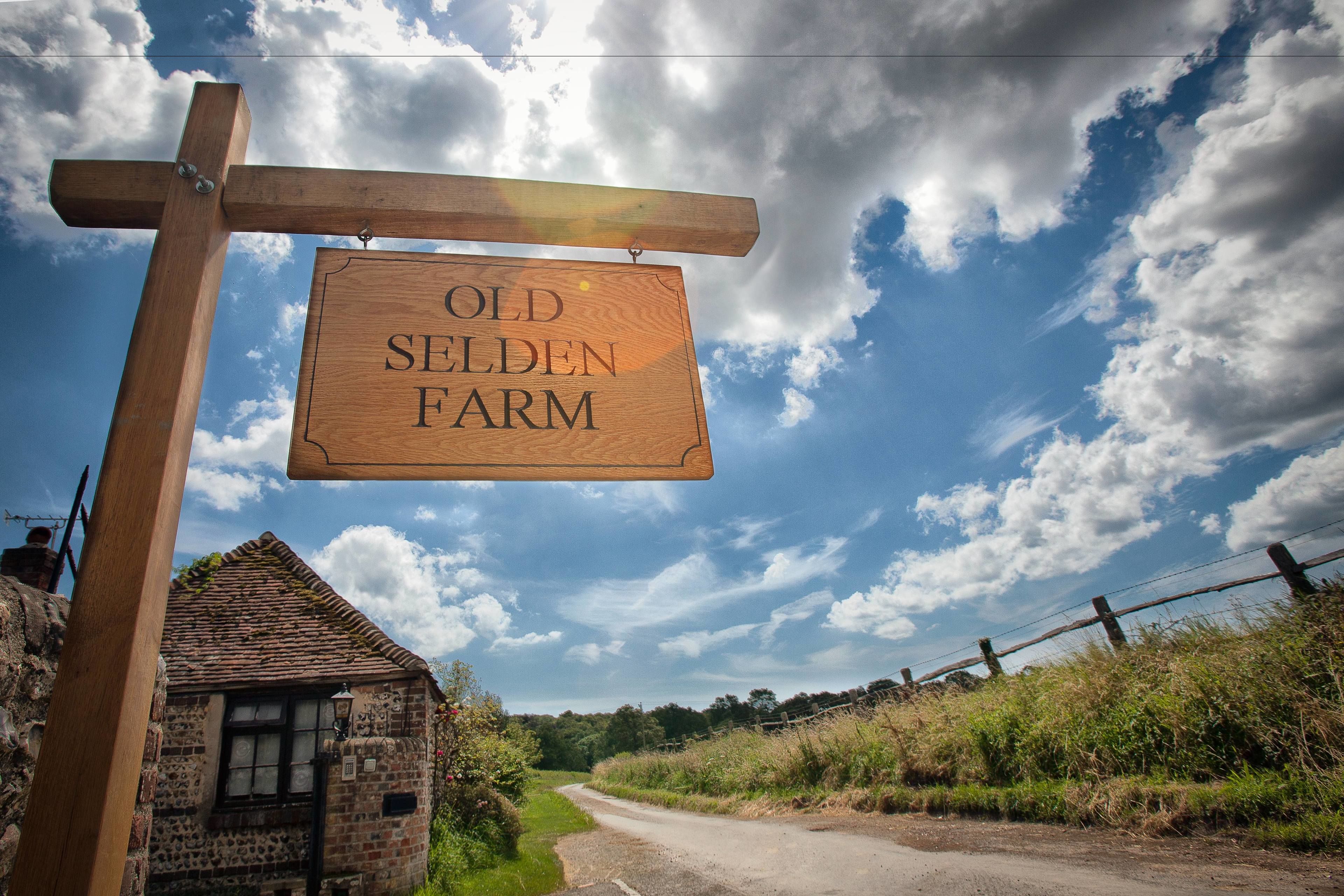 A wooden sign reading "Old Selden Farm" against a rural backdrop with a clear sky.