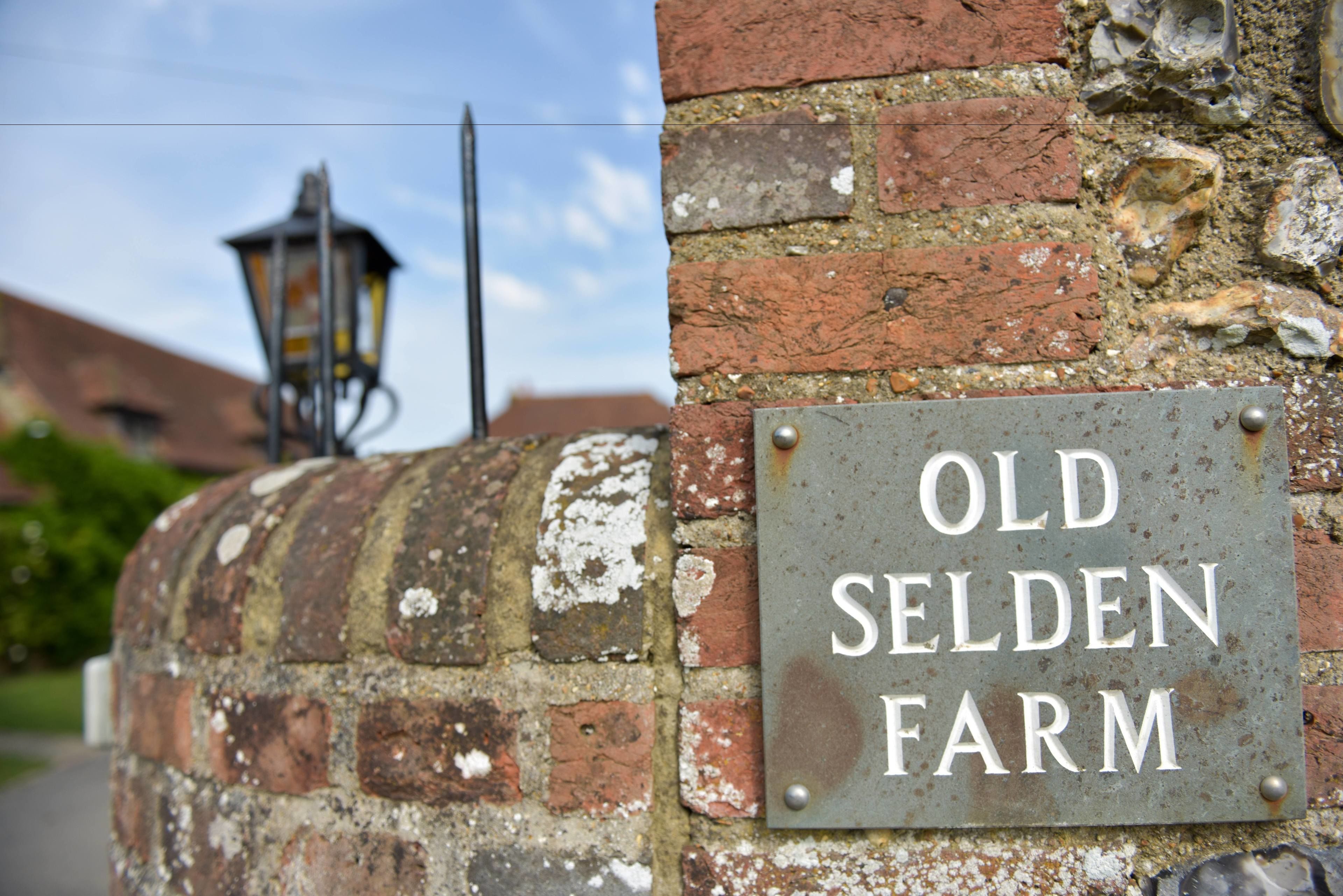 A weathered metal sign on a brick wall reading "Old Selden Farm."