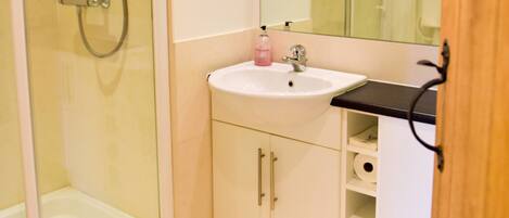A bathroom with a glass-enclosed shower, a white sink, and a mirror above it.