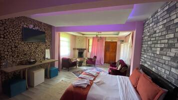 Un dormitorio con cama, escritorio, sillas, chimenea y pared de piedra.