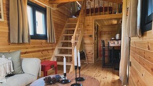 A cozy cabin interior with a wooden staircase, a round dining table with candles, a sofa, and a small red table. - Agva Green River Otel - Adults Only (Sile)