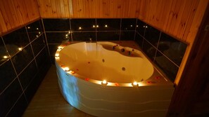 Un jacuzzi en una cabaña de madera con paredes de baldosas negras y suelo de baldosas.