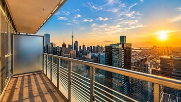 A balcony with a city skyline view, including a prominent tower, during sunset.