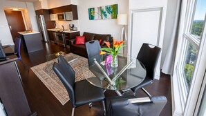 A modern living space with a dining area, kitchen, and a view through a large window. - Altitude Suites on Yonge (Toronto)