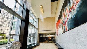 A modern interior with large windows, a glass railing, and a prominent abstract painting on the wall. - Altitude Suites on Yonge (Toronto)