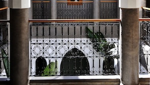 A courtyard with a central archway, columns, and a decorative railing. - Riad Houma (Marrakech)