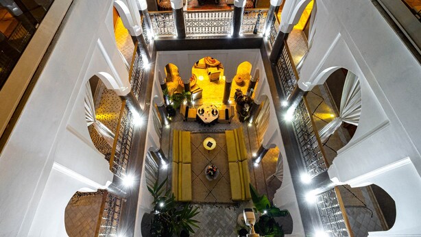 A multi-level atrium with a central seating area, multiple staircases, and decorative arches. - Riad Houma (Marrakech)