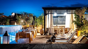 An outdoor dining area with tables and chairs, a pool, and a covered seating area. - Riad Houma (Marrakech)