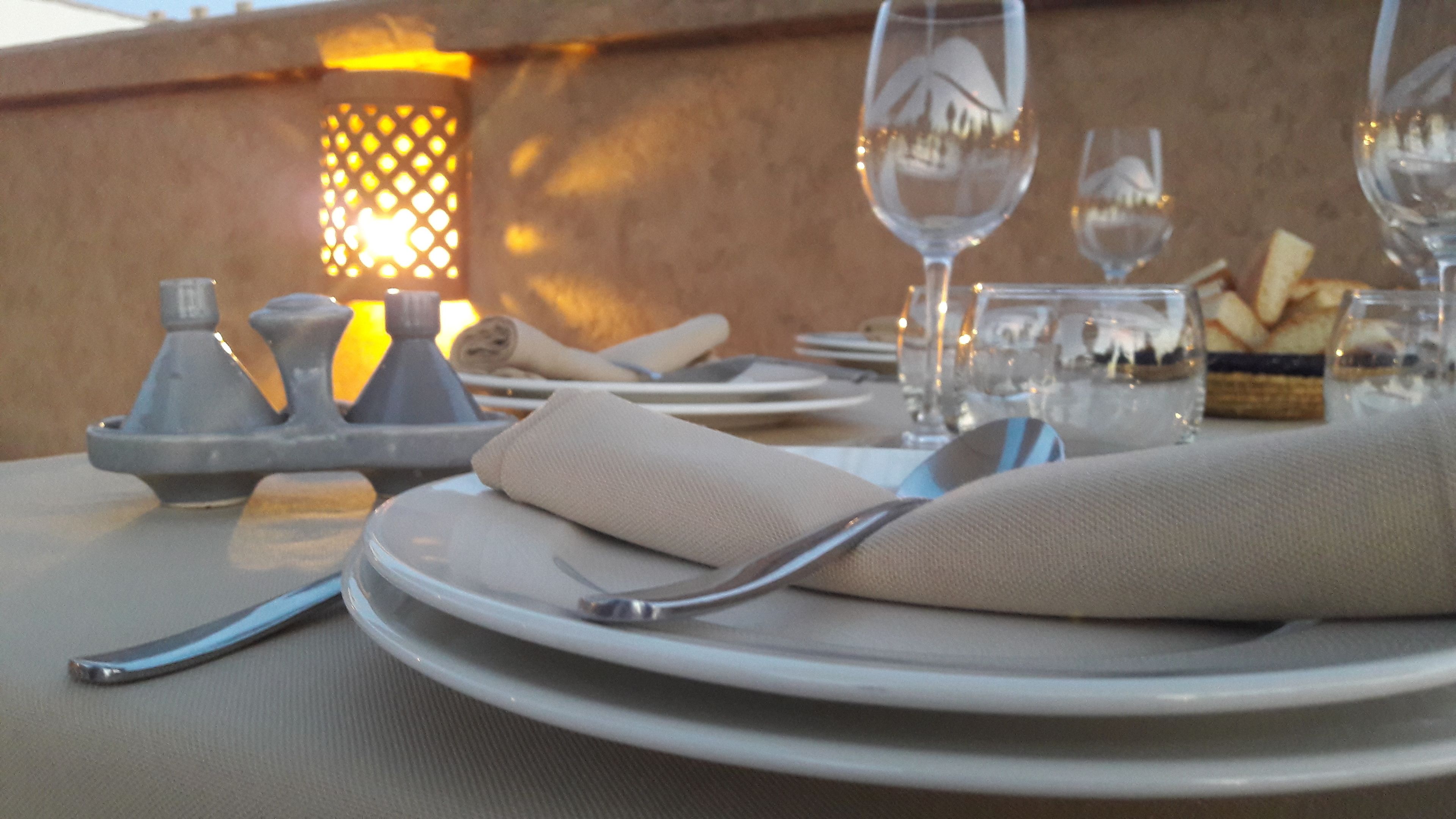 A table set for a meal with plates, cutlery, glasses, and a candle holder.