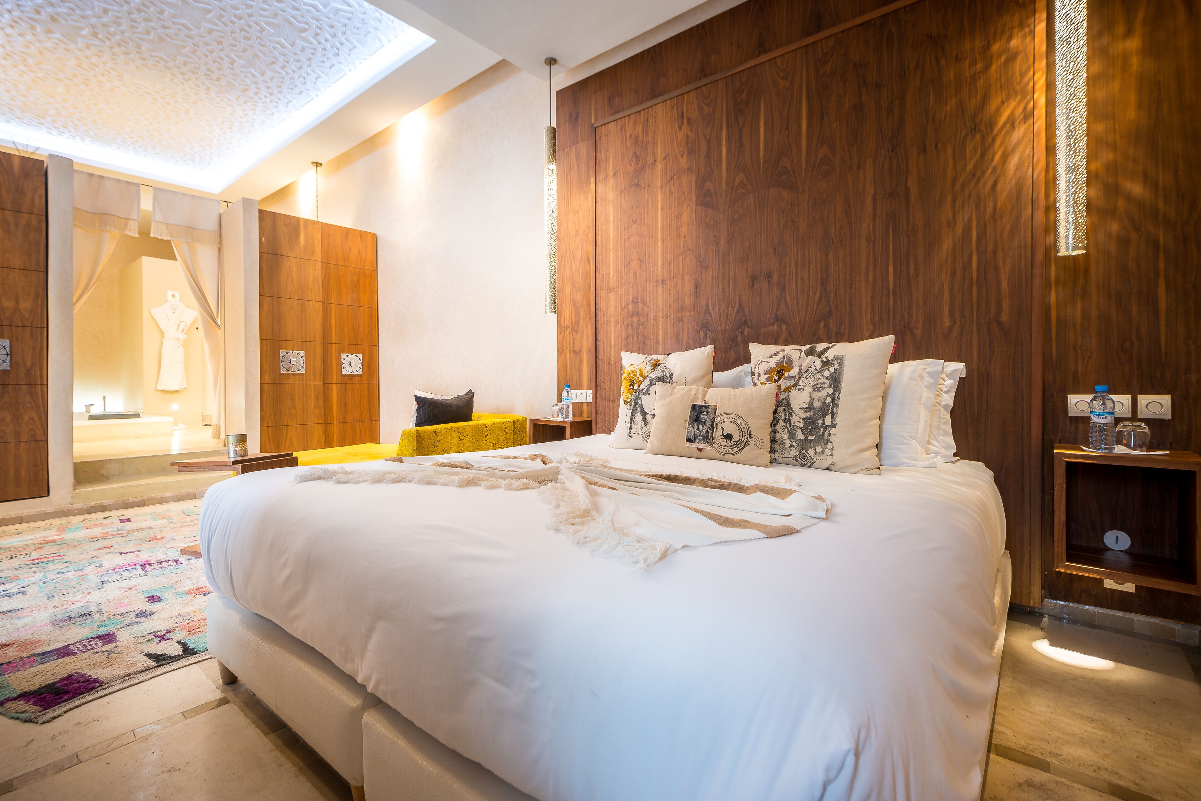 Une chambre moderne avec un grand lit, un lambris en bois et un tapis à motifs.
