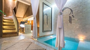 A spa area with a glass-enclosed pool, a staircase, and a reception desk. - Riad Houma (Marrakech)