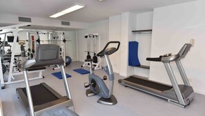 Un gimnasio con cintas de correr, elípticas y equipo de levantamiento de pesas.