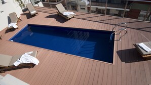 Una piscina al aire libre con sillas de descanso y una terraza de madera.