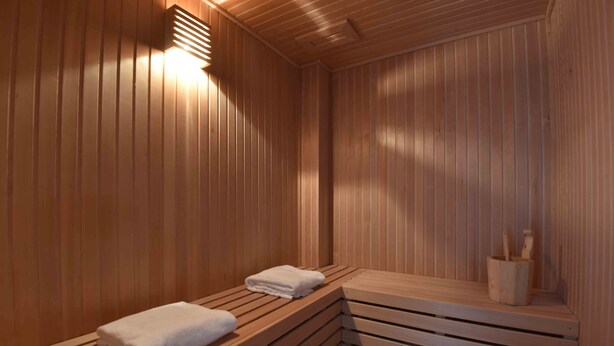 Una sauna con bancos de madera y una pared de madera, además de una lámpara.