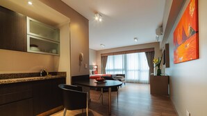Una cocina moderna con armarios oscuros, encimera de granito y comedor con mesa y sillas negras.