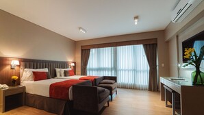 Una habitación de hotel con una cama grande, dos mesitas de noche, un escritorio y una silla.