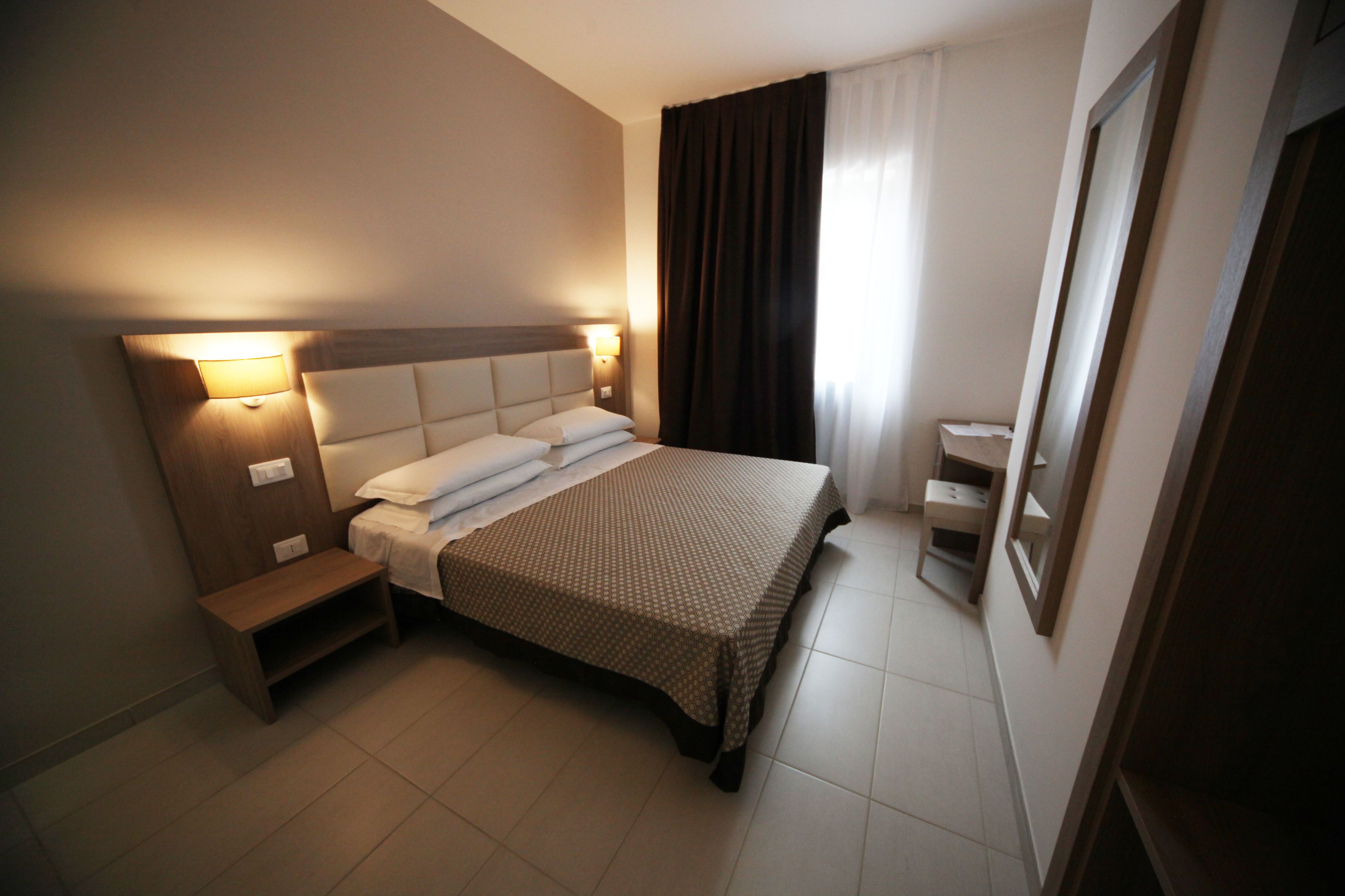 Ein ordentlich eingerichtetes Hotelzimmer mit einem großen Bett, Nachttischen und einem Beistelltisch.