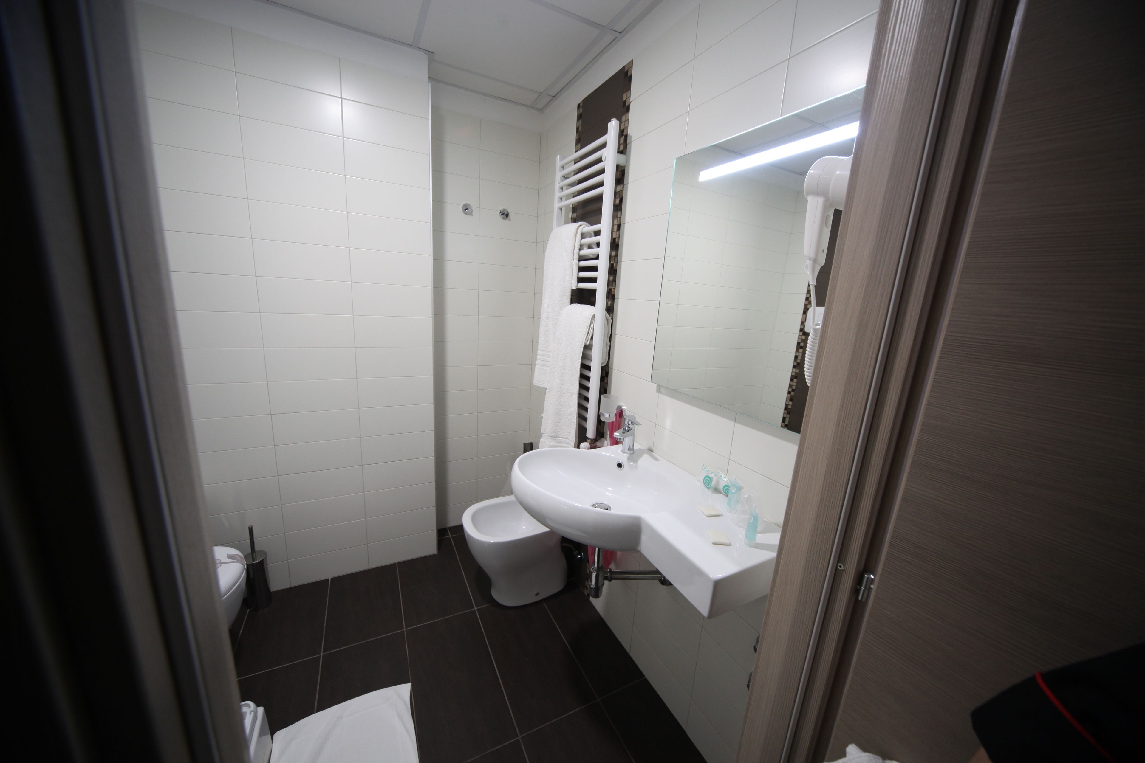 A bathroom with a toilet, bidet, sink, and a mirror.