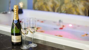Una botella de Moët & Chandon y dos copas sobre una superficie de mármol, con una bañera al fondo.