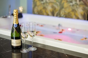 Una botella de Moët & Chandon y dos copas sobre una superficie de mármol, con una bañera al fondo.
