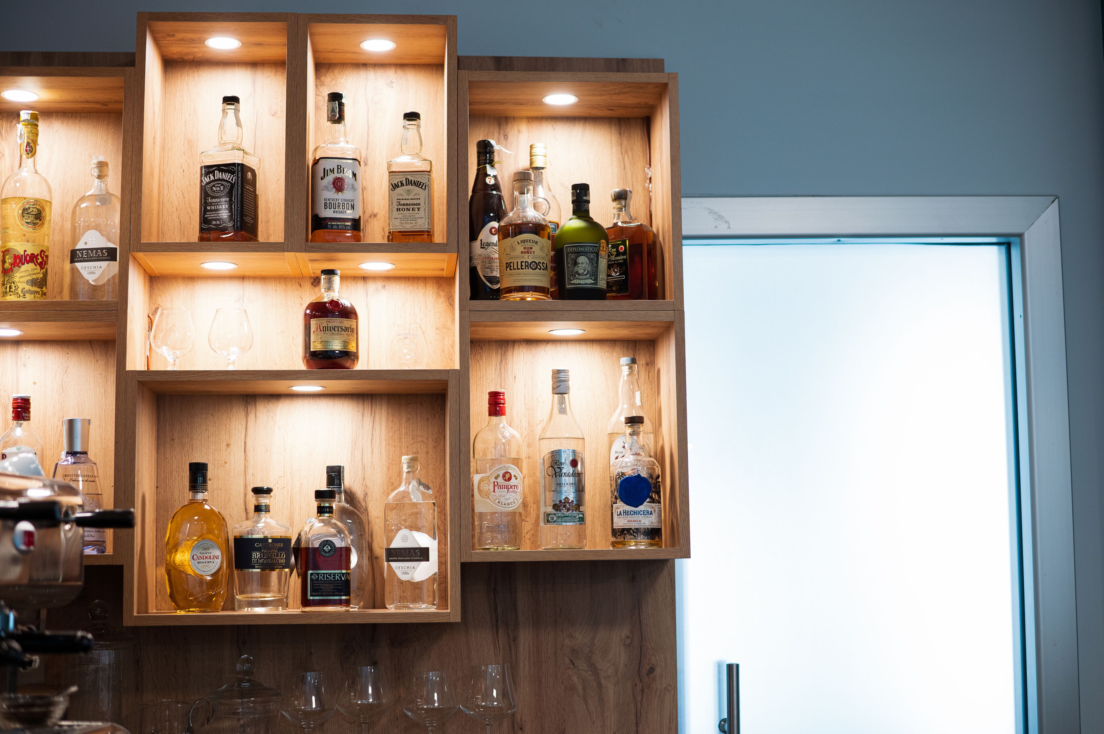 Un mueble bar de madera con varias botellas y vasos.