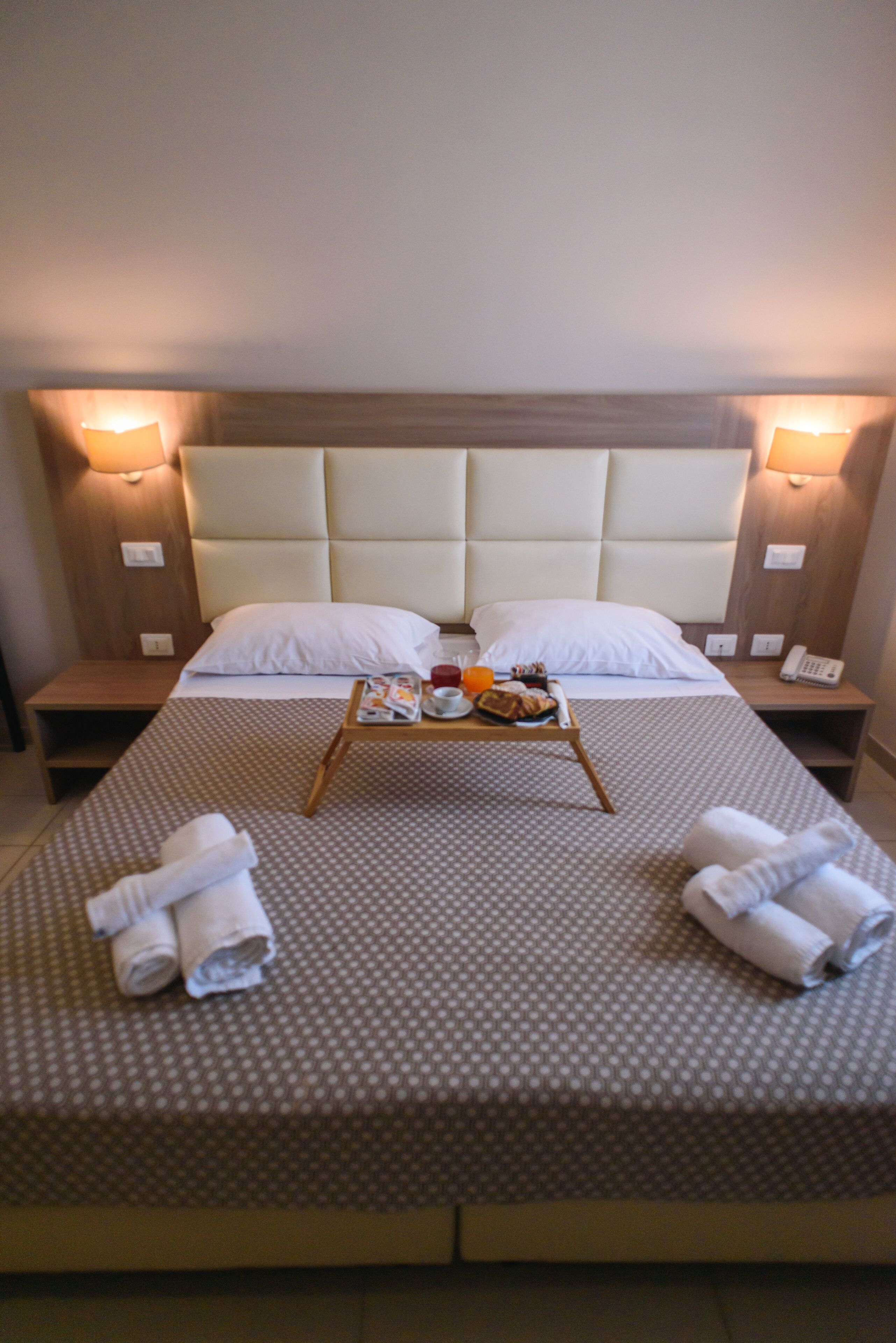 Habitación de hotel con una cama grande, dos mesitas de noche y un cabecero con iluminación integrada.