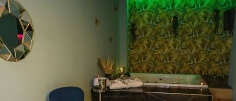 Um banheiro moderno com uma banheira grande, uma cadeira azul e uma mesa redonda pequena com um objeto decorativo.