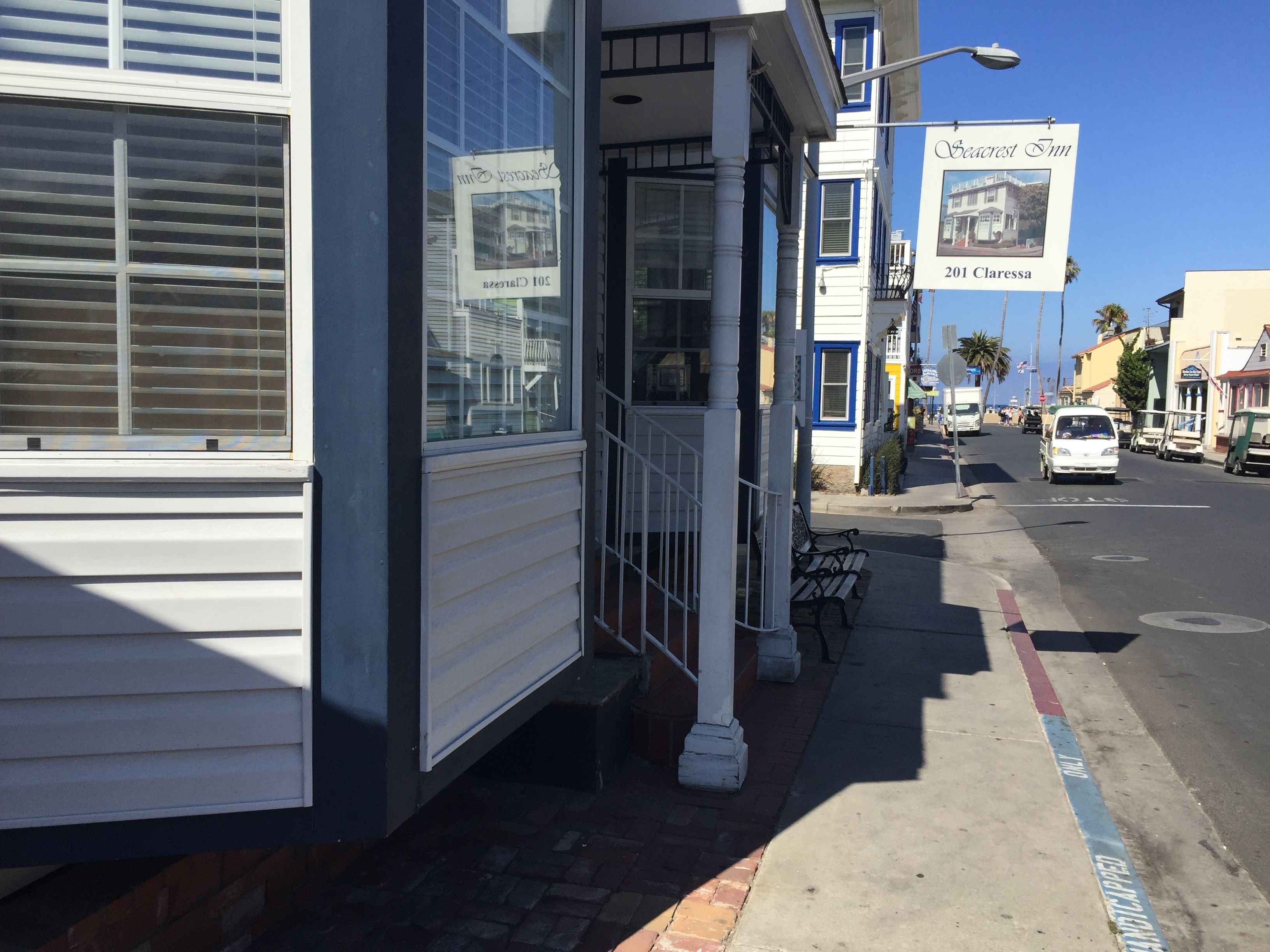 A building with a sign for Seacrest Inn, a street with parked cars, and a sidewalk with a handicapped parking sign.