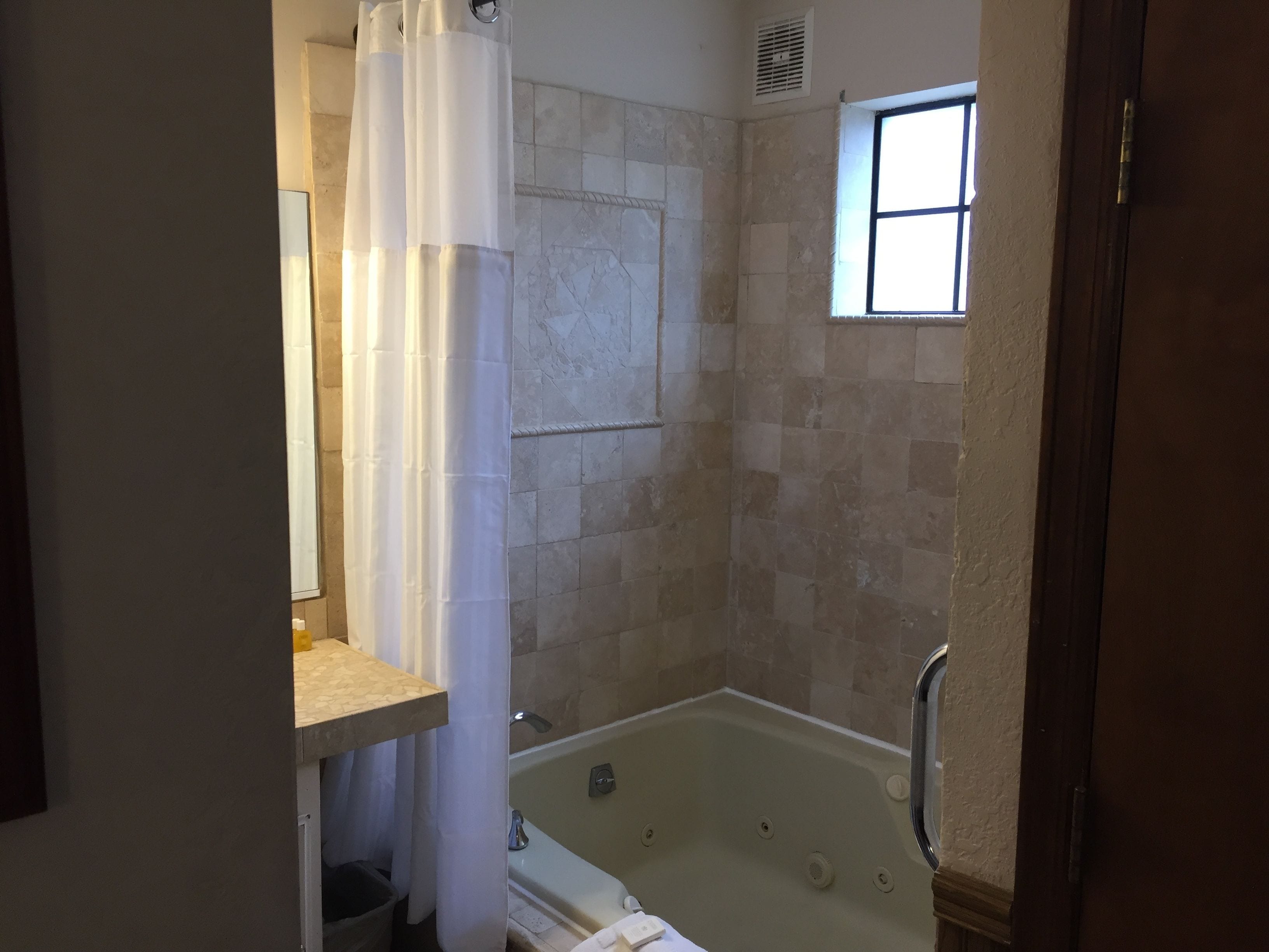 Un baño con bañera, zona de ducha y ventana que proporciona luz natural.
