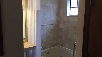 Un baño con bañera, zona de ducha y ventana que proporciona luz natural.