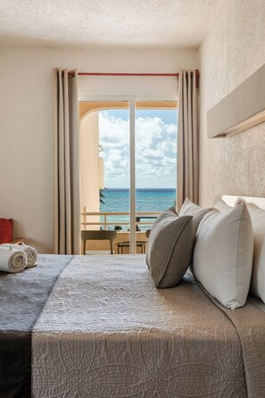 Et hotelværelse med seng, havudsigt og balkon med bord og stole.