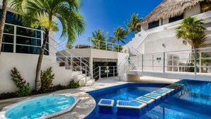 Una piscina con jacuzzi, escaleras y palmeras.