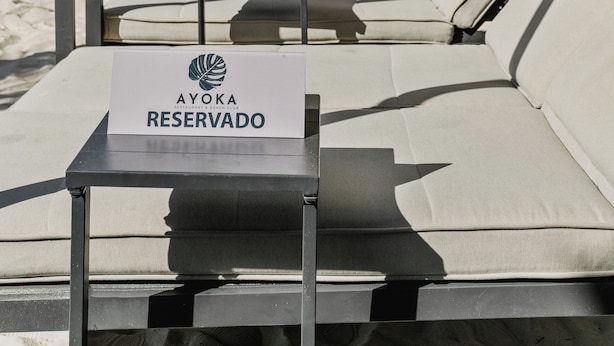 A beachside seating area with a reserved sign, lounge chairs, and a view of the ocean.