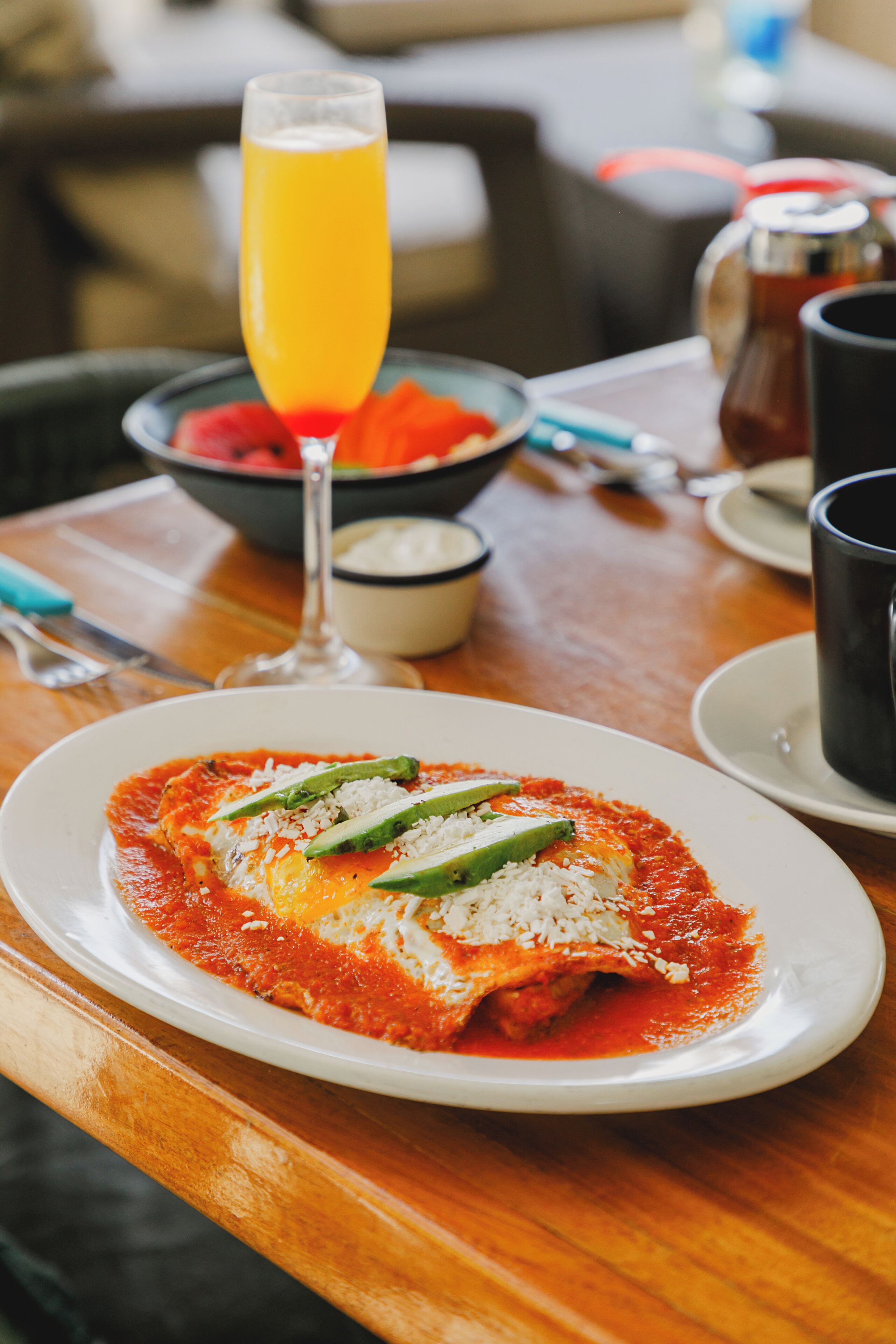 Una mesa de comedor con un plato de comida, un vaso de jugo de naranja y una jarra de té.