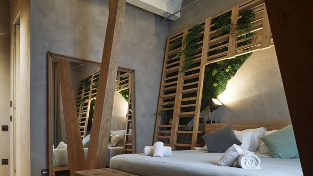 Et moderne soveværelse med en stor seng, en træbænk og et unikt loftsdesign.