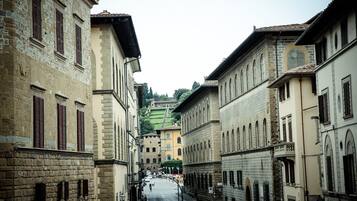 Rua estreita ladeada por edifícios históricos com janelas em arco e fachadas de pedra.