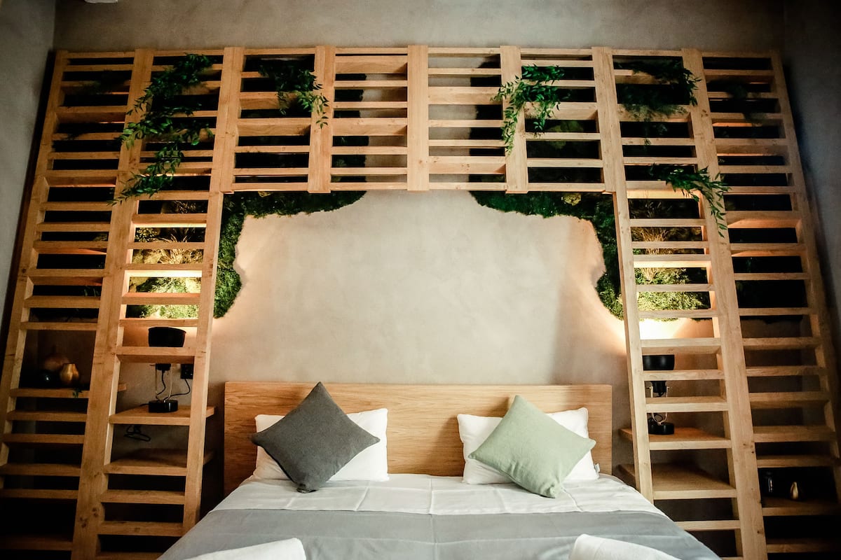 A bedroom with a wooden headboard, two pillows, and a bed.