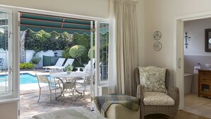 Quarto com vista para uma piscina, uma cadeira de vime, uma mesa de jantar com cadeiras e uma pequena cozinha.