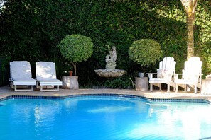 A swimming pool with white lounge chairs and a decorative fountain. - Carslogie House (Gqeberha (Port Elizabeth))