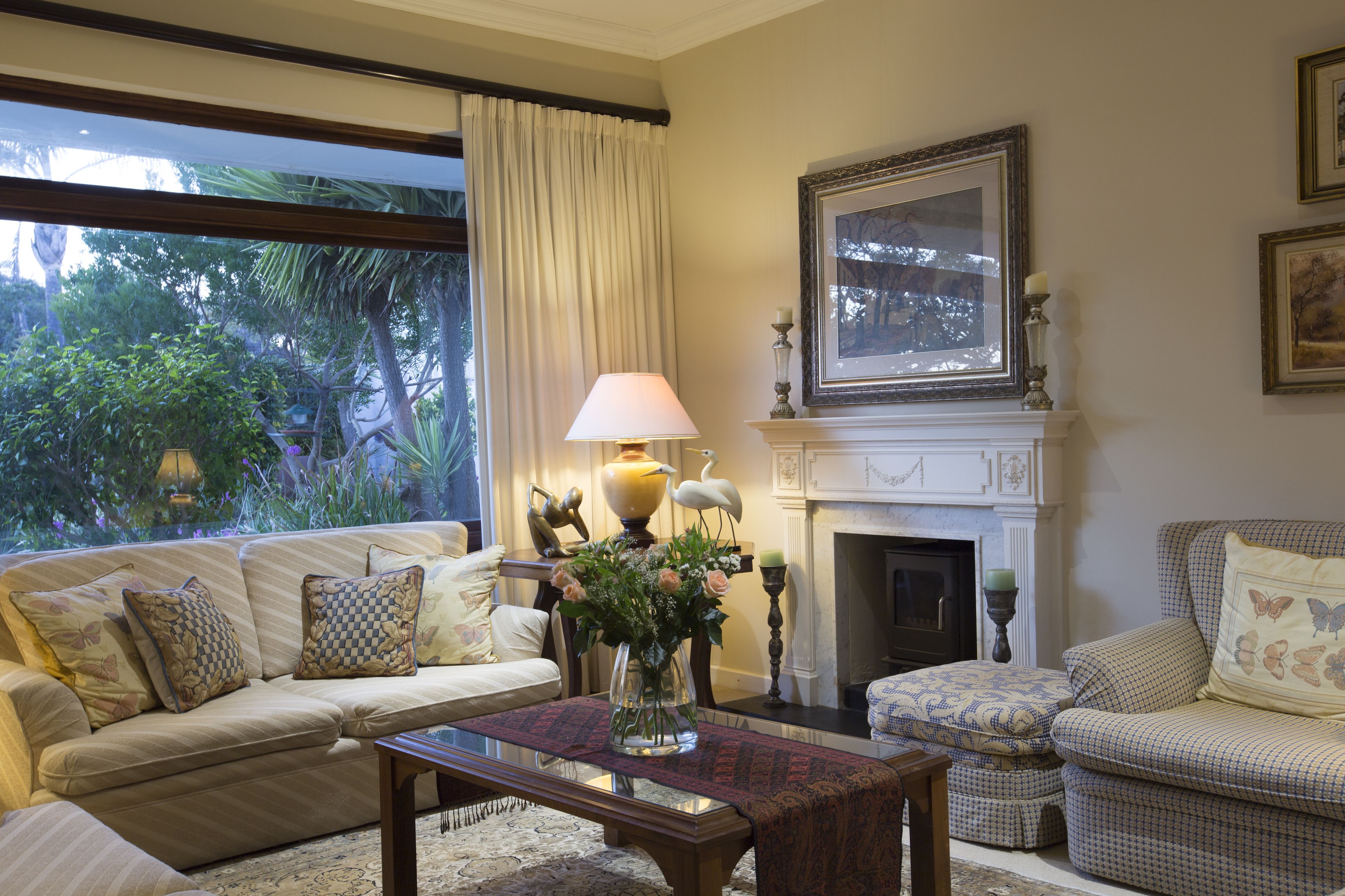 A living room with a sofa, armchair, and ottoman, a fireplace, and a window with curtains.