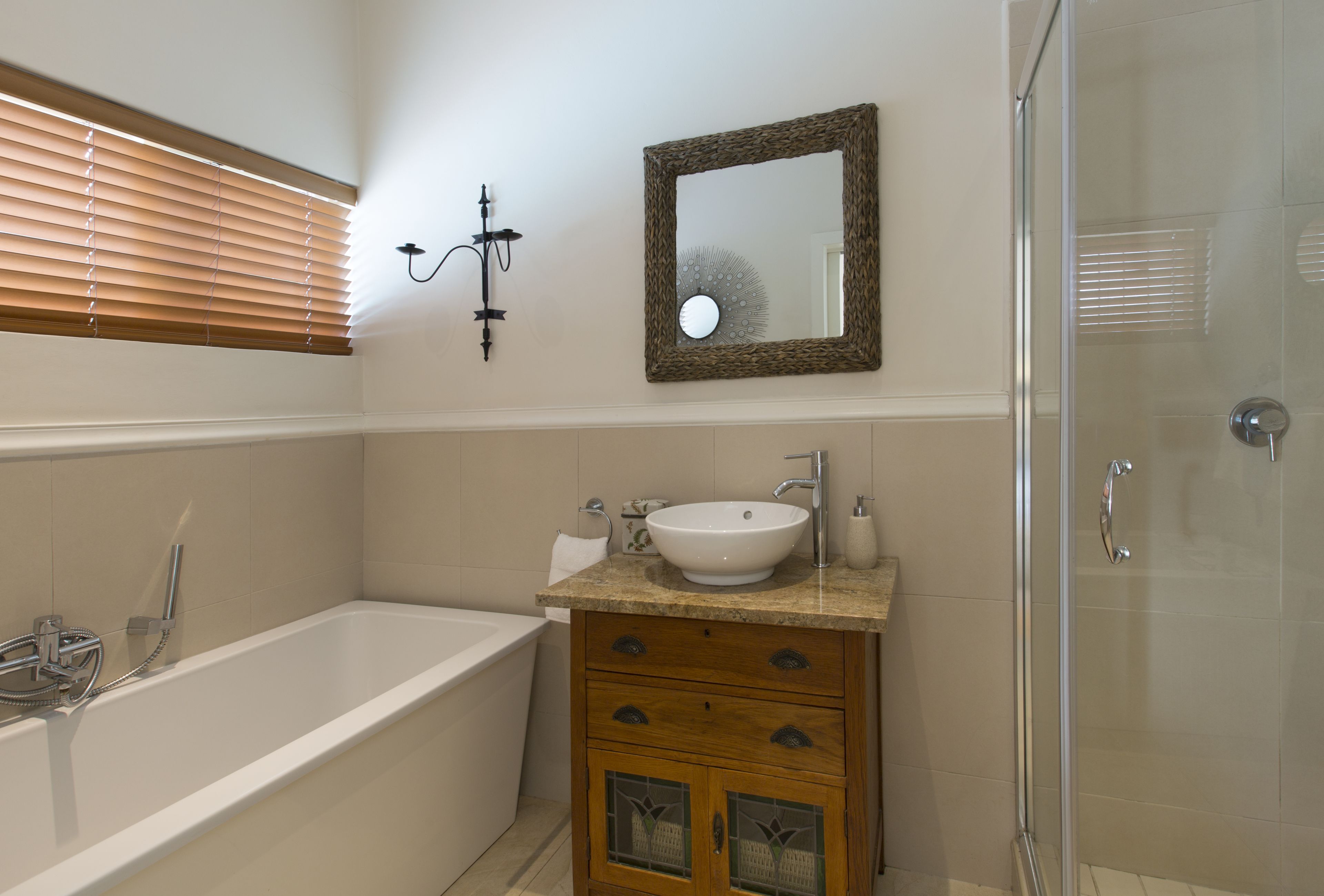 A bathroom with a bathtub, a sink, a mirror, and a shower.
