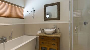 A bathroom with a bathtub, a sink, a mirror, and a shower.