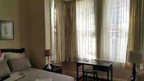 Een hotelkamer met een bed, een bureau, een stoel en een lamp.