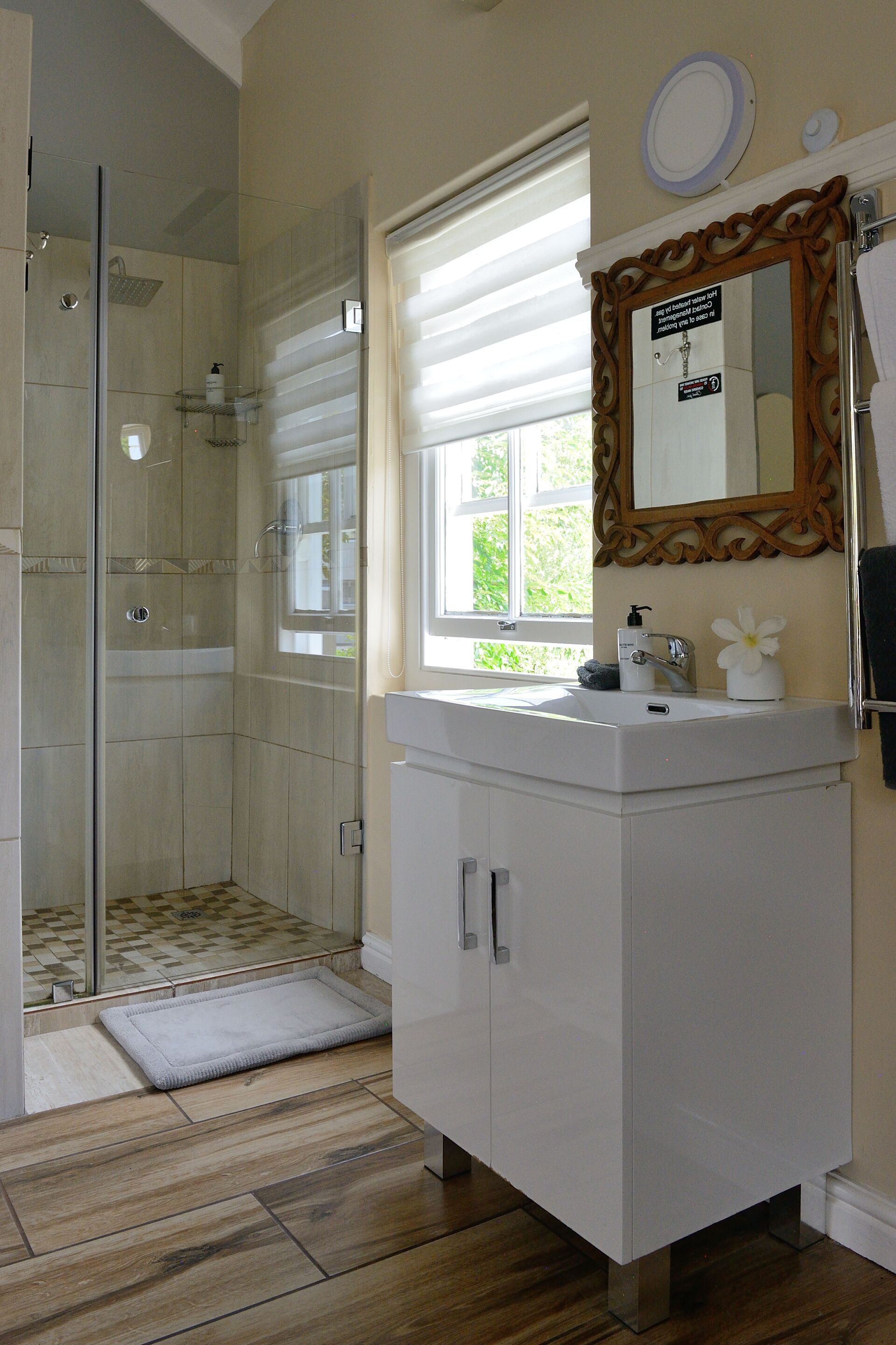 Un baño con ducha, lavabo, espejo y ventana.