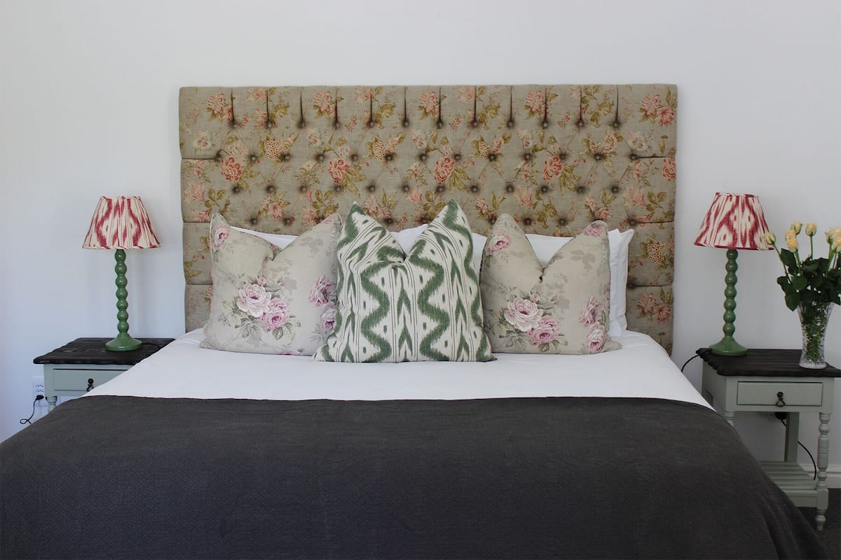 A bed with a floral headboard, multiple pillows, and two bedside tables with lamps.